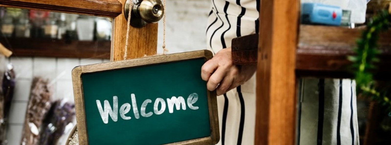 a welcome small business sign hanging on a door