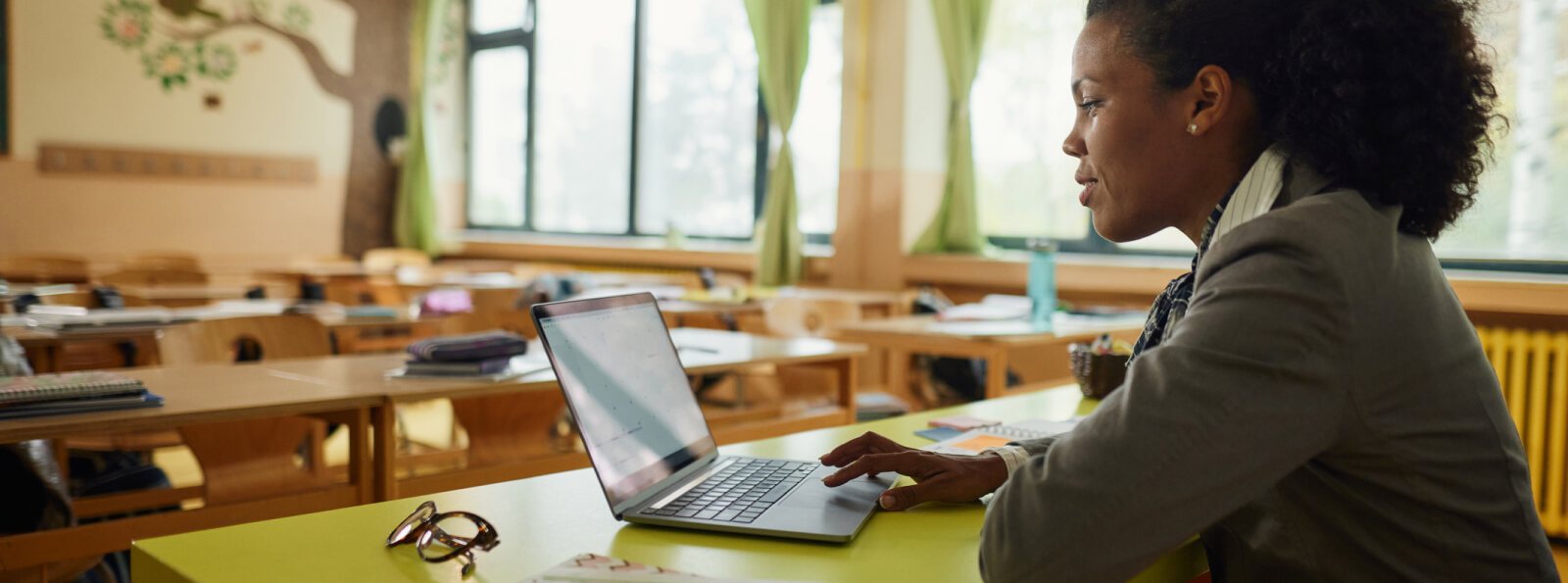 a teacher sitting at her desk with a laptop